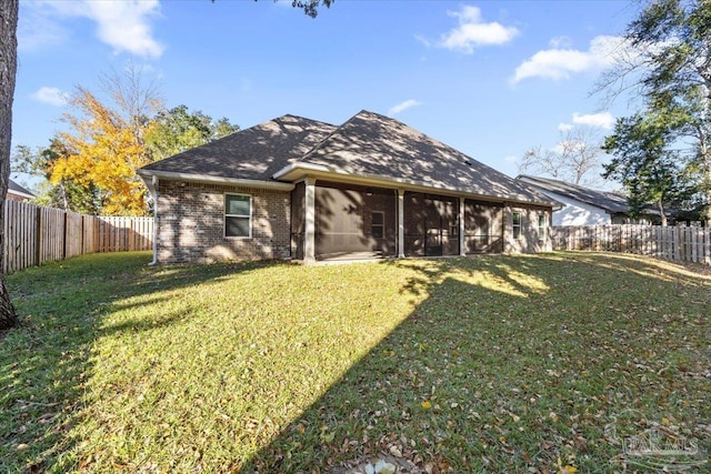 rear view of house featuring a sunroom and a yard