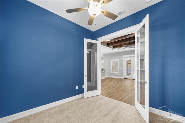 empty room with carpet, ceiling fan, french doors, and beamed ceiling