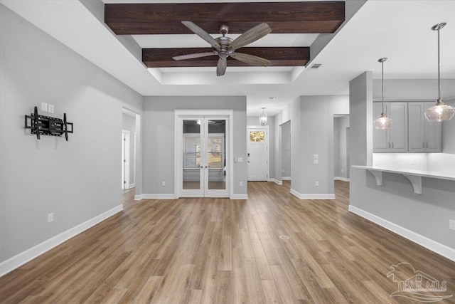 unfurnished living room featuring beamed ceiling, french doors, light hardwood / wood-style flooring, and ceiling fan