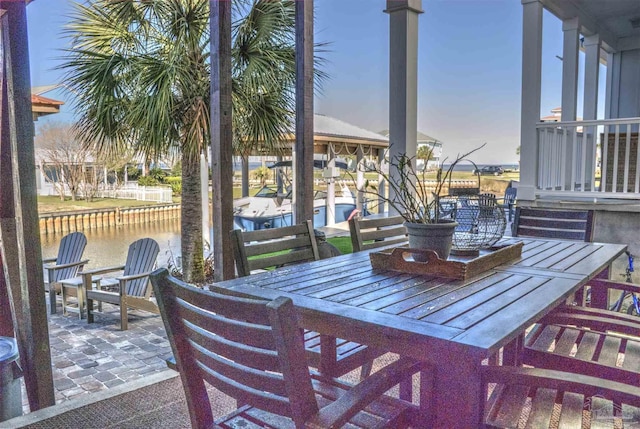 exterior space featuring a water view, a boat dock, and outdoor dining space