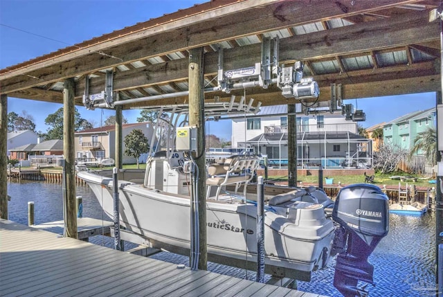 dock area with a water view, boat lift, and a residential view