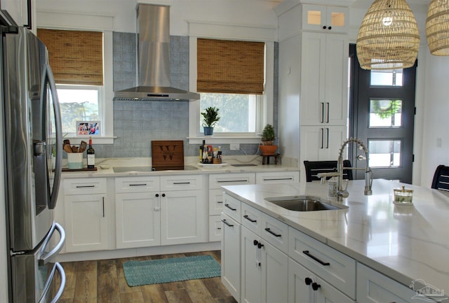 kitchen with dark wood-style floors, white cabinetry, wall chimney range hood, stainless steel fridge, and black electric cooktop