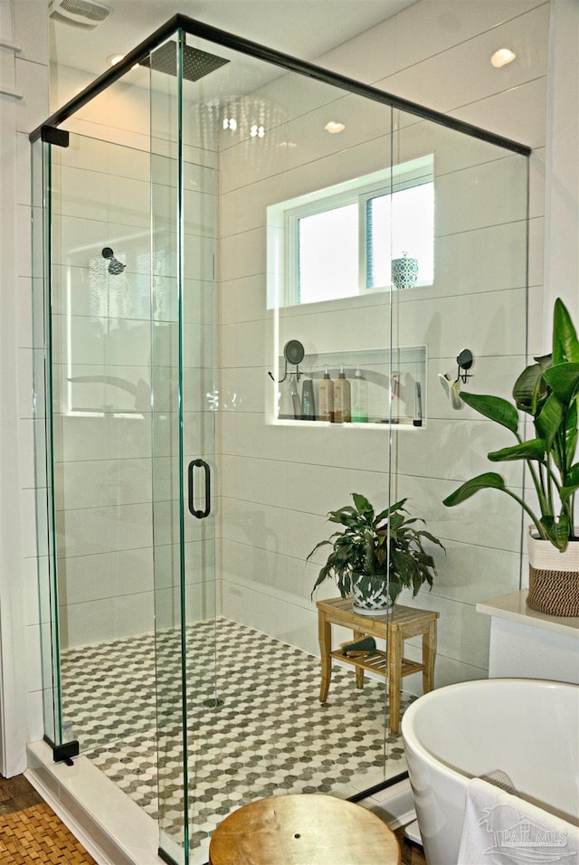 bathroom featuring a stall shower, tile walls, and a soaking tub