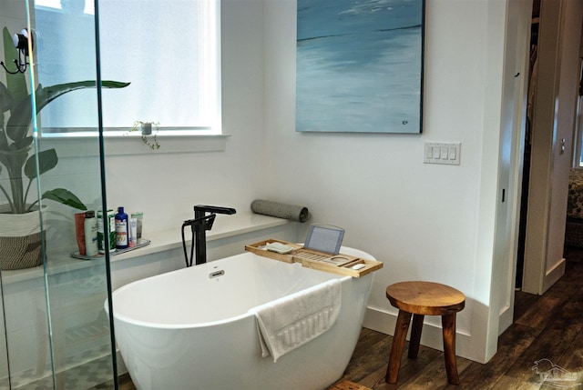 full bathroom featuring a sink, a soaking tub, and wood finished floors