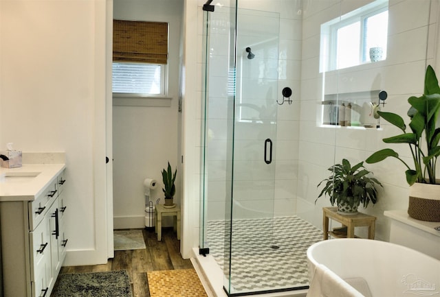 bathroom featuring a freestanding tub, wood finished floors, vanity, baseboards, and a shower stall