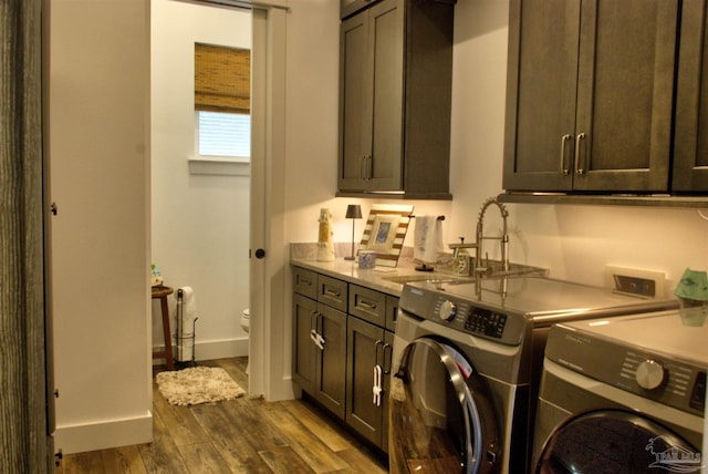 washroom with cabinet space, baseboards, dark wood-style flooring, washer and dryer, and a sink