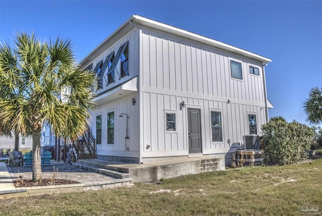 exterior space with board and batten siding, a yard, and central air condition unit