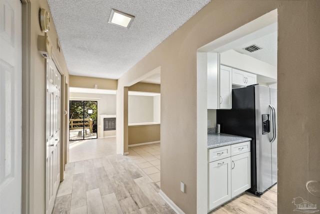 kitchen featuring a textured ceiling, white cabinetry, stainless steel refrigerator with ice dispenser, and light hardwood / wood-style floors