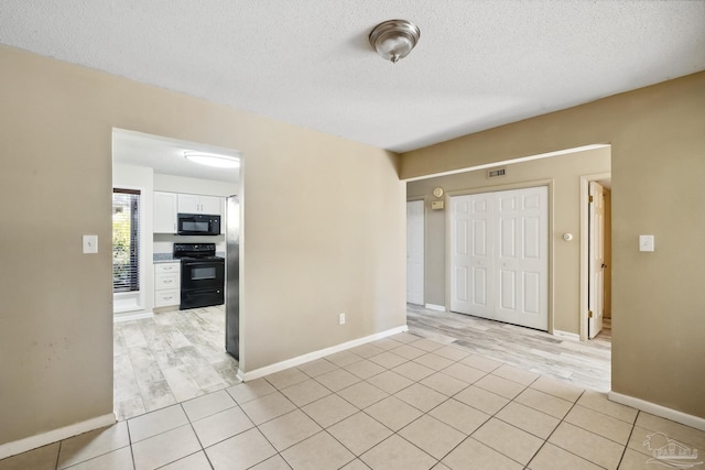 unfurnished room with light wood-type flooring and a textured ceiling