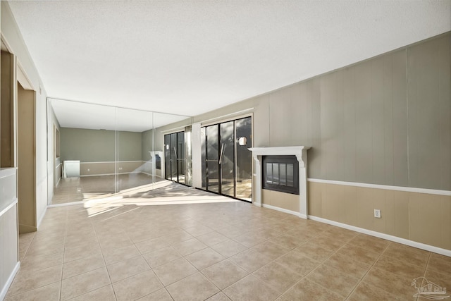 unfurnished living room with a textured ceiling and light tile patterned floors