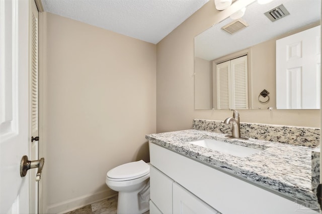 bathroom with tile patterned floors, vanity, a textured ceiling, and toilet