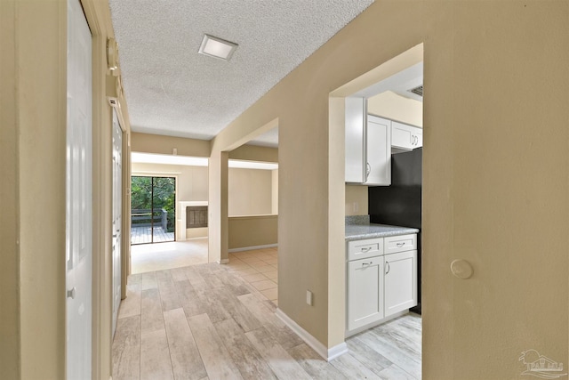 hall featuring light hardwood / wood-style flooring and a textured ceiling