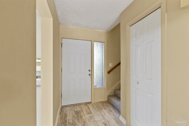 foyer entrance with light hardwood / wood-style flooring and a textured ceiling