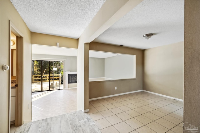 spare room featuring light tile patterned flooring and a textured ceiling