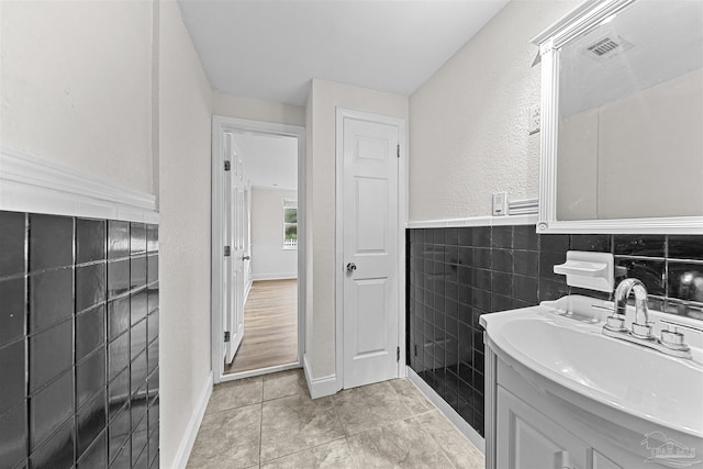 bathroom with visible vents, a wainscoted wall, tile patterned floors, vanity, and tile walls