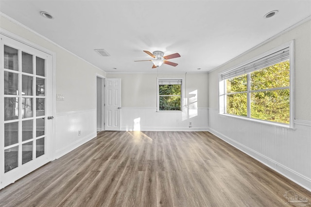 unfurnished room with a wainscoted wall, crown molding, visible vents, and wood finished floors