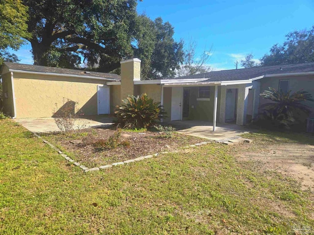 rear view of house featuring a lawn and stucco siding