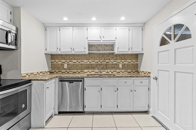 kitchen featuring appliances with stainless steel finishes, dark stone counters, white cabinets, and a sink