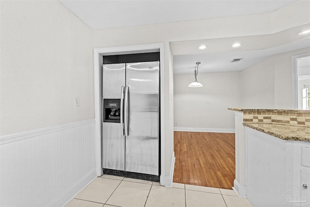 kitchen featuring a wainscoted wall, decorative light fixtures, stainless steel refrigerator with ice dispenser, and light tile patterned flooring