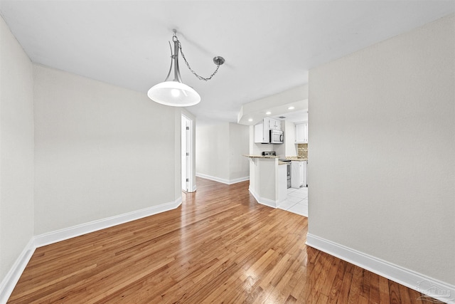 unfurnished living room featuring light wood-type flooring and baseboards