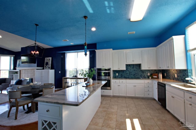 kitchen featuring white cabinetry, hanging light fixtures, plenty of natural light, and stainless steel double oven