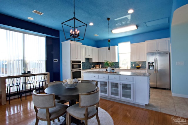 kitchen with light hardwood / wood-style floors, a healthy amount of sunlight, appliances with stainless steel finishes, and white cabinets