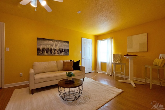 living room with ceiling fan, wood-type flooring, and a textured ceiling