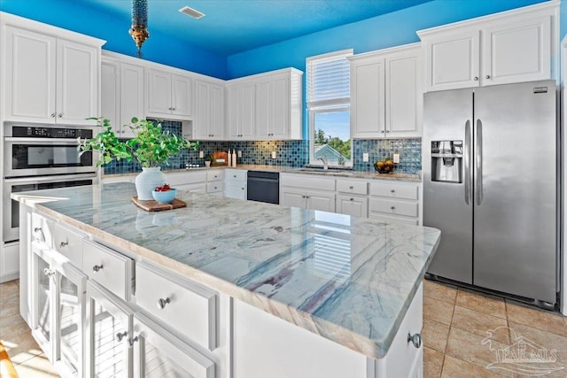 1280 Mahogany Mill Rd, Pensacola, FL 32507 - kitchen featuring appliances with stainless steel finishes, tasteful backsplash, white cabinetry, a sink, and light stone countertops