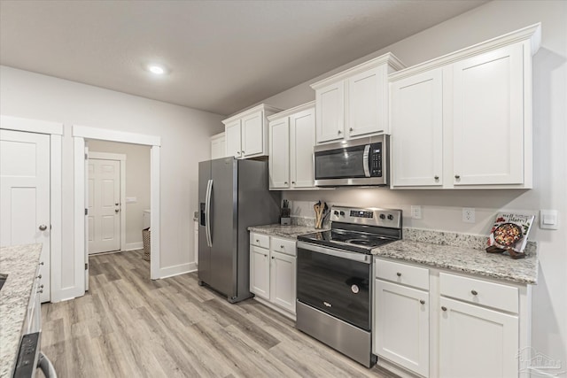 kitchen with white cabinets, light stone countertops, stainless steel appliances, and light hardwood / wood-style flooring