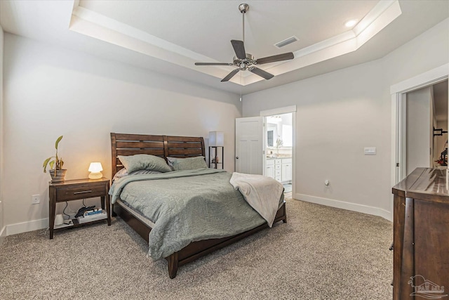 bedroom with ceiling fan, connected bathroom, a raised ceiling, and carpet floors