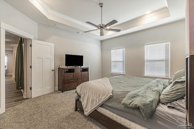 carpeted bedroom featuring ceiling fan and a tray ceiling