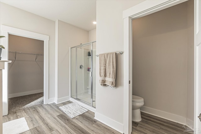 bathroom with an enclosed shower, toilet, and hardwood / wood-style floors