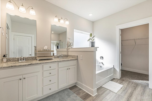 bathroom with wood-type flooring, a tub to relax in, and vanity