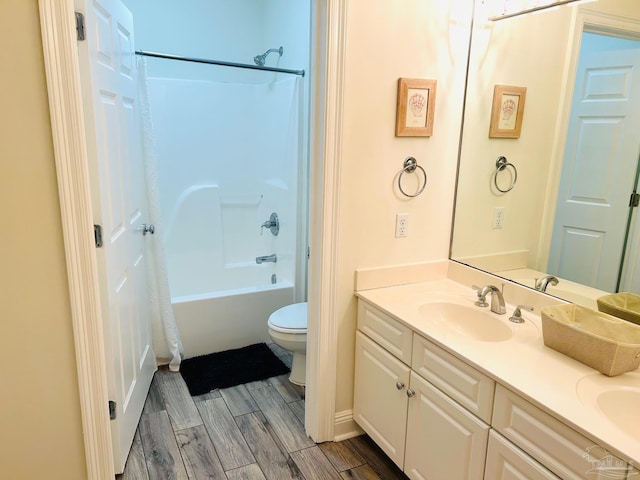 bathroom with wood finish floors, double vanity, toilet, washtub / shower combination, and a sink