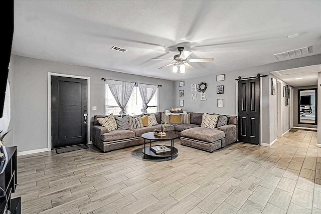 living room with a barn door, a textured ceiling, and ceiling fan