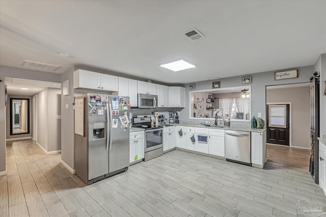 kitchen featuring a barn door, appliances with stainless steel finishes, white cabinets, and ceiling fan