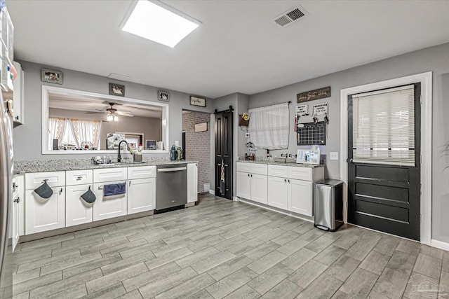 kitchen with white cabinetry, sink, stainless steel dishwasher, ceiling fan, and light stone countertops