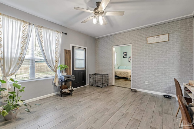 interior space with ceiling fan, brick wall, and light hardwood / wood-style flooring