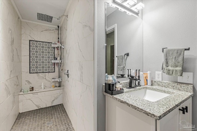 bathroom with crown molding, tiled shower, and vanity