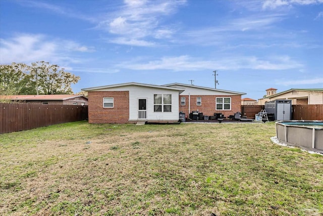 back of property with a fenced in pool, a patio area, and a lawn