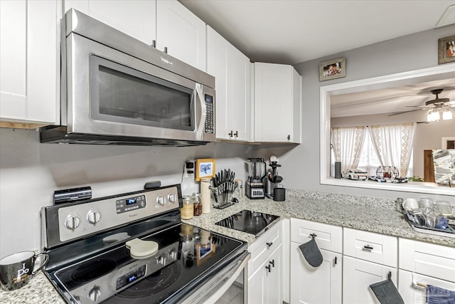 kitchen with stainless steel appliances, white cabinetry, and light stone countertops