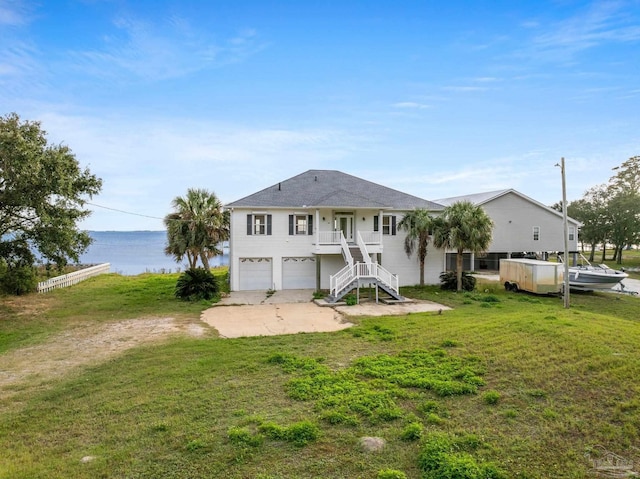 rear view of house with a lawn, a water view, a porch, and a garage