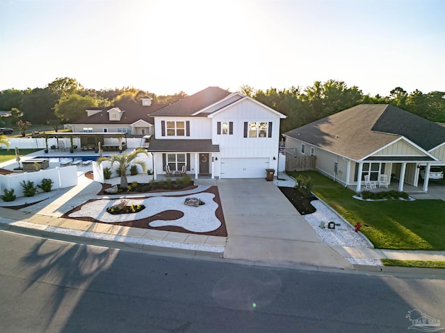 view of front facade with covered porch, a front yard, fence, an attached garage, and concrete driveway