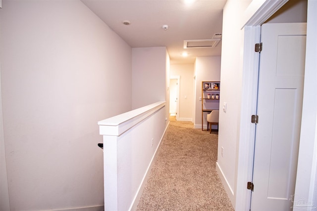 hall with light carpet, attic access, baseboards, and an upstairs landing