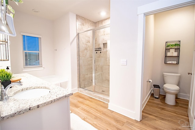 bathroom with baseboards, toilet, a shower stall, vanity, and wood finished floors