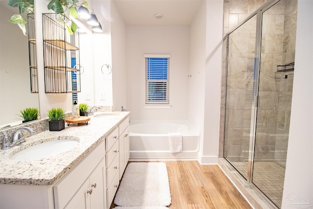 full bathroom with a garden tub, a sink, a stall shower, and wood finished floors