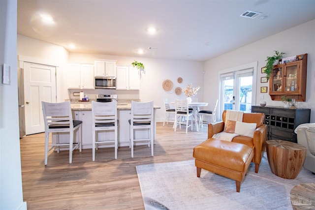 living room with recessed lighting, visible vents, and light wood-style flooring