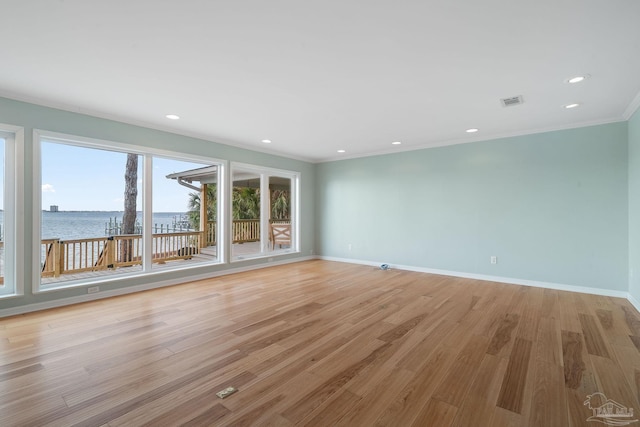 spare room with crown molding, light wood-type flooring, and a water view