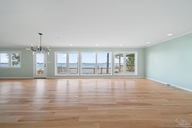 unfurnished living room with ornamental molding, a water view, a notable chandelier, and light wood-type flooring