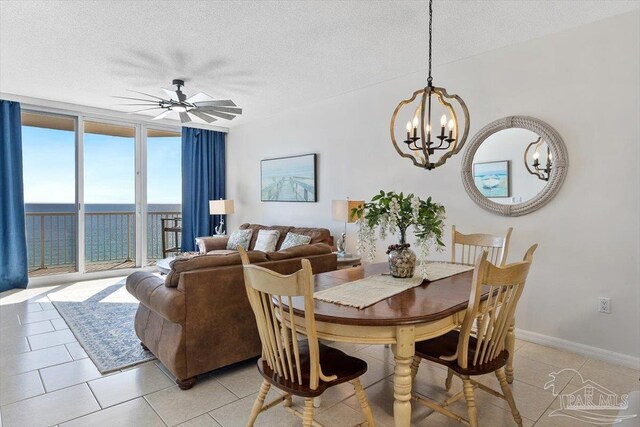 tiled dining area with a water view, a textured ceiling, and a wall of windows